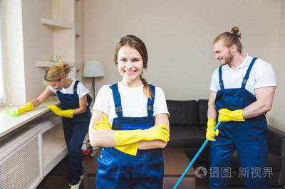 在工作過程中使用專業(yè)設(shè)備的清潔服務(wù)。專業(yè)的小廚房清潔, 沙發(fā)干洗, 窗戶和地板清洗。穿制服、工作服和橡膠手套的男人和女人